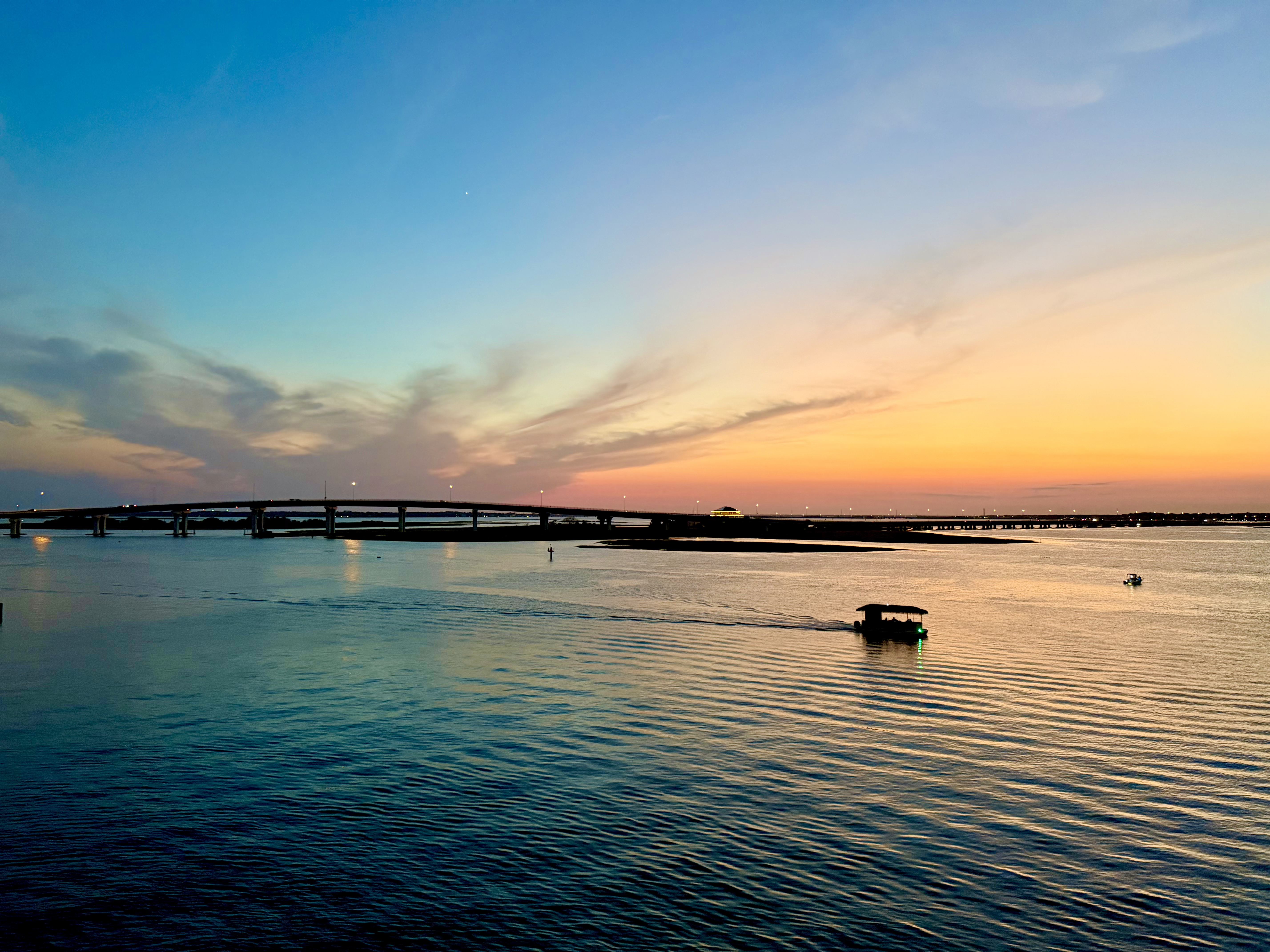 Boats crossing the bay beneath a bridge at sunset